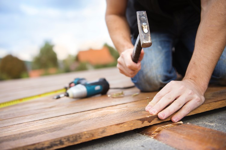 handyman-installs-wood-boards-hammer-nail